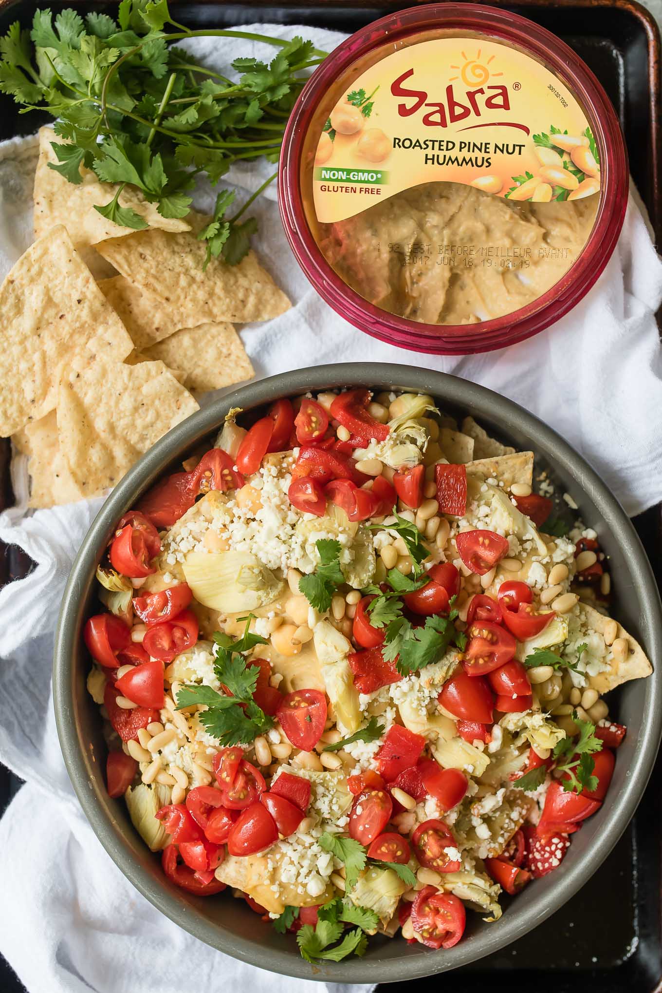 Mediterranean Nachos are a delicious gluten free and vegetarian snack/appetizer loaded with hummus, veggies, feta and more- a fun spin on the classic Tex Mex dish.