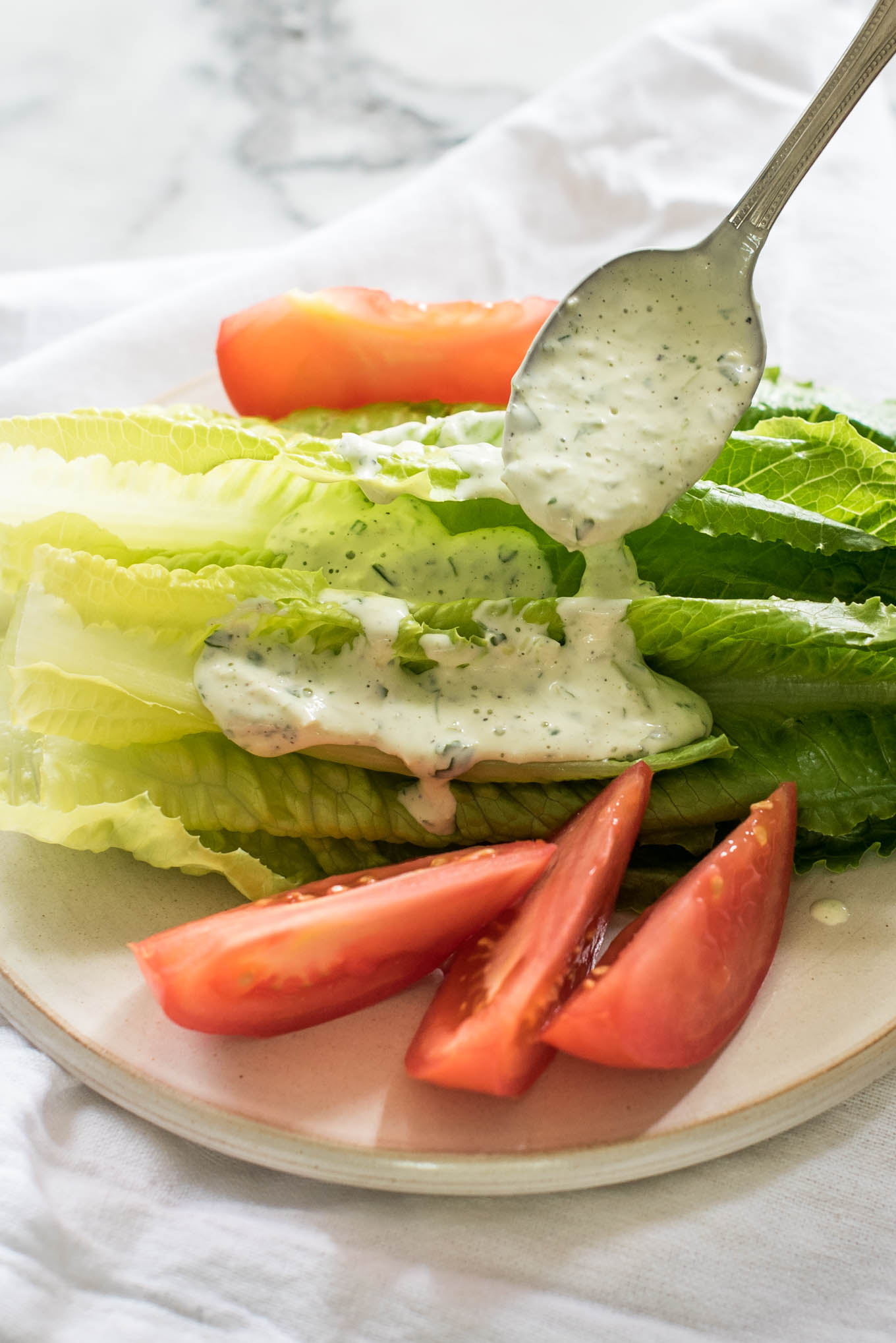 spoon drizzling dressing on salad