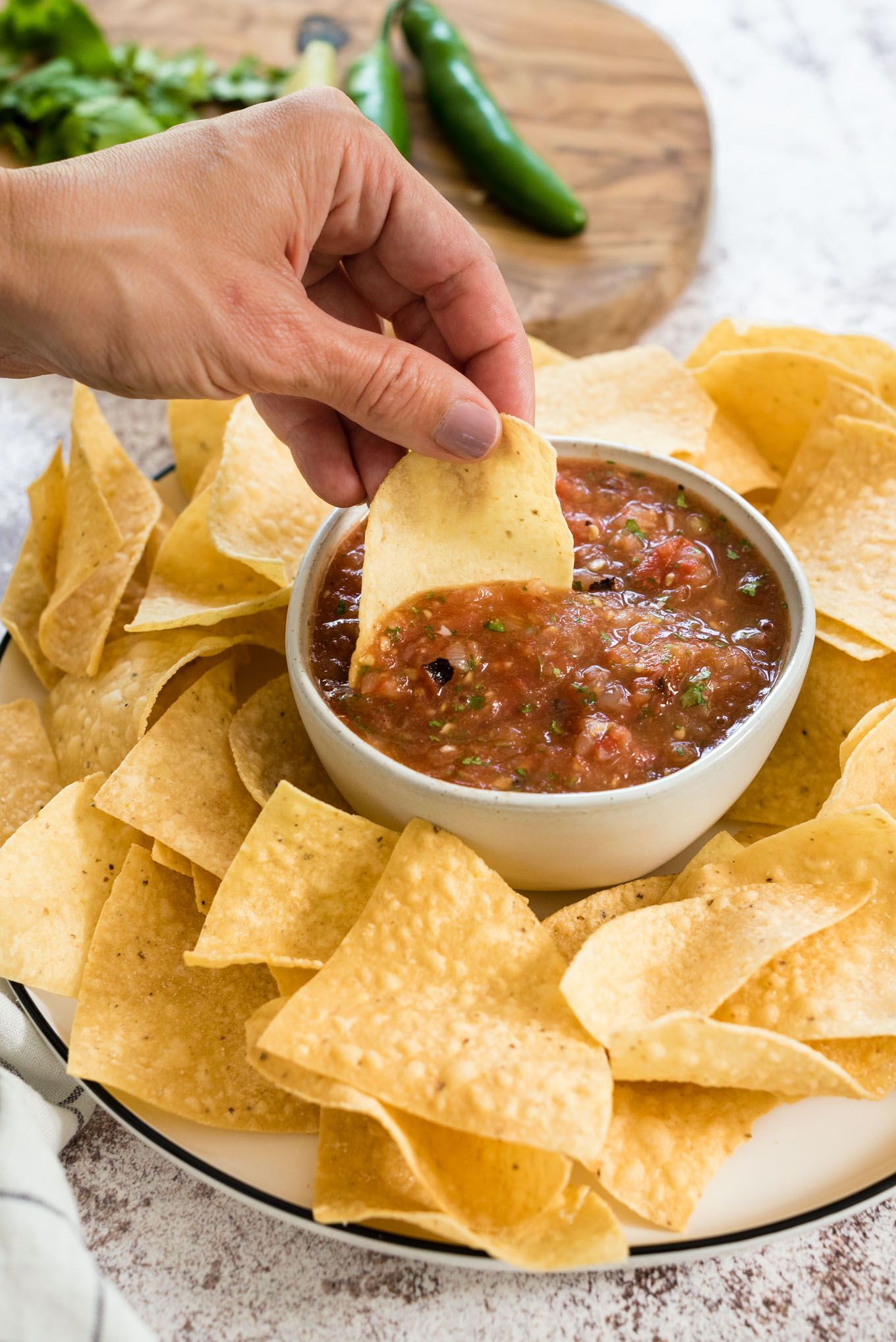Hand dipping chip into bowl of salsa