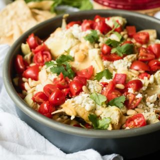 Mediterranean Nachos are a delicious gluten free and vegetarian snack/appetizer loaded with hummus, veggies, feta and more- a fun spin on the classic Tex Mex dish.