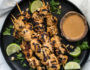 Chicken Satay on a black plate with peanut sauce
